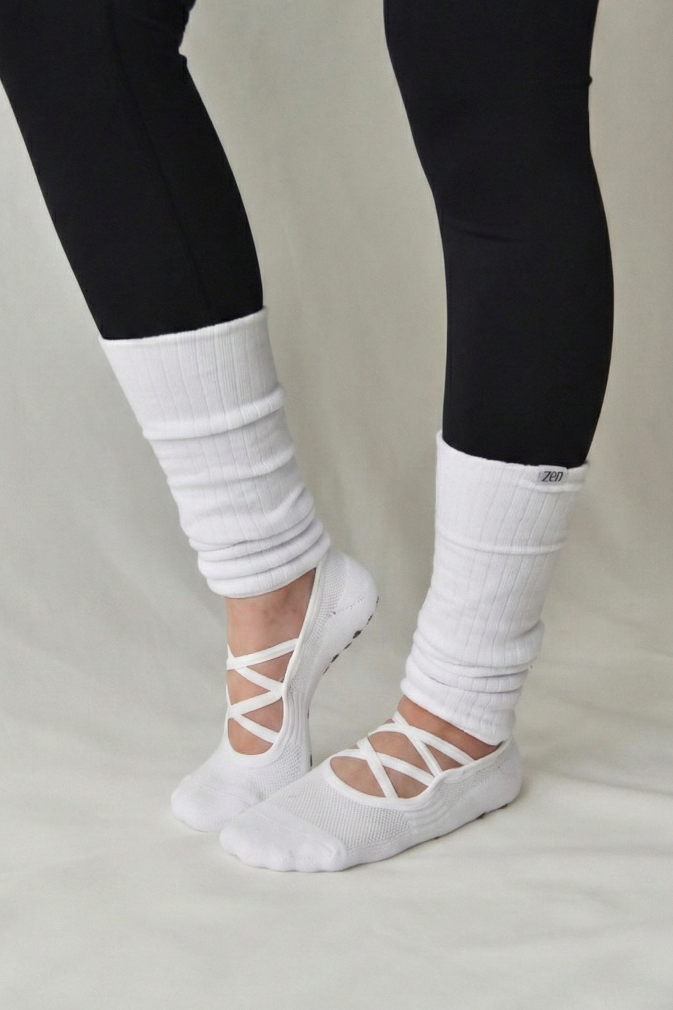 White socks with lace-up design worn with black leggings on a neutral background